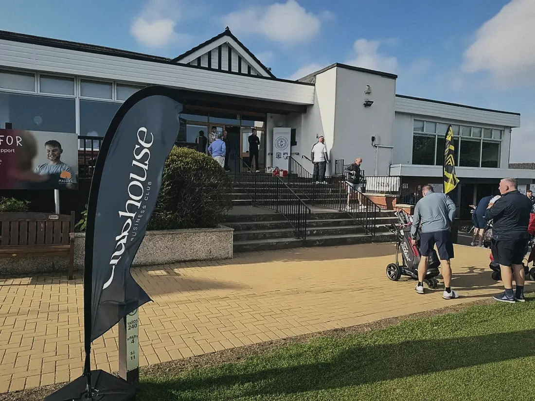 Golfers and a Clubhouse flag outside the clubhouse at Airdrie Golf Club