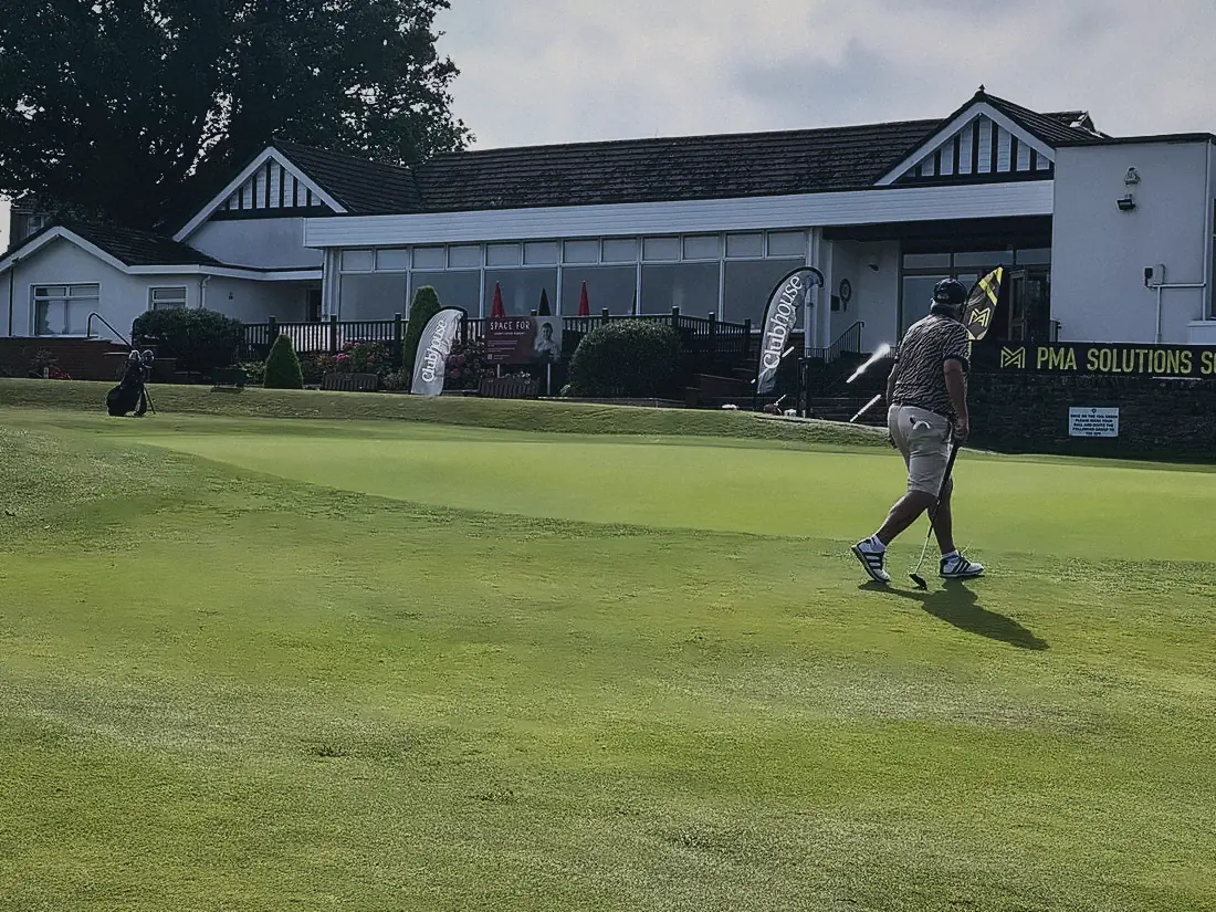 A golfer driving off in front of the Airdrie clubhouse