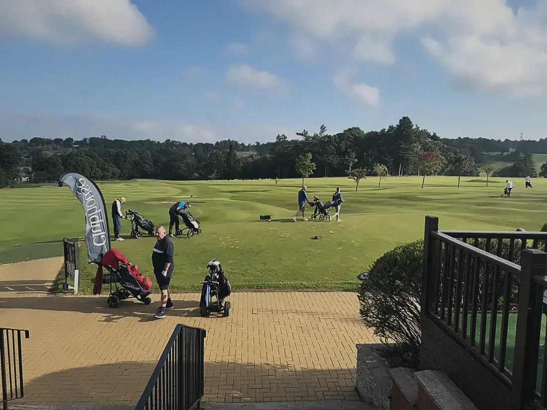 Buggies and players lined up by a Clubhouse flag