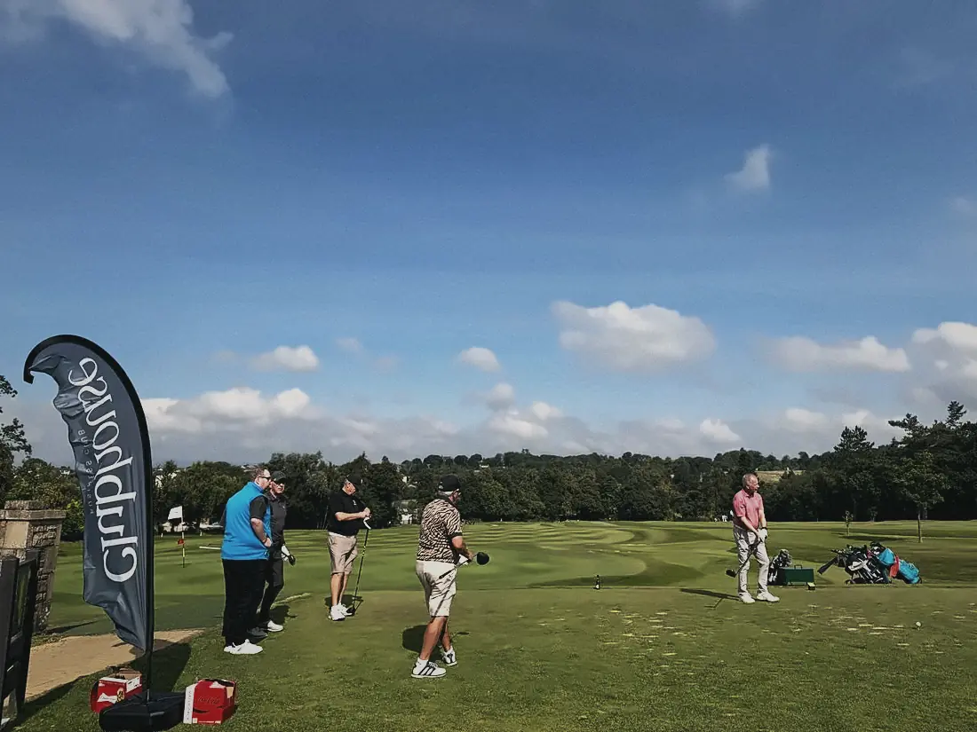 A group teeing off on a bright August day